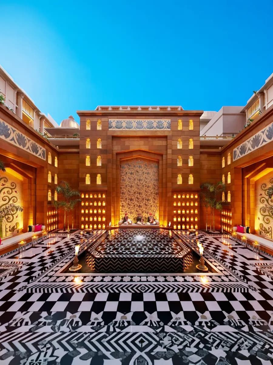 The Leela Palace Udaipur seen across the lake at sunset, marble jharokhas reflected on water