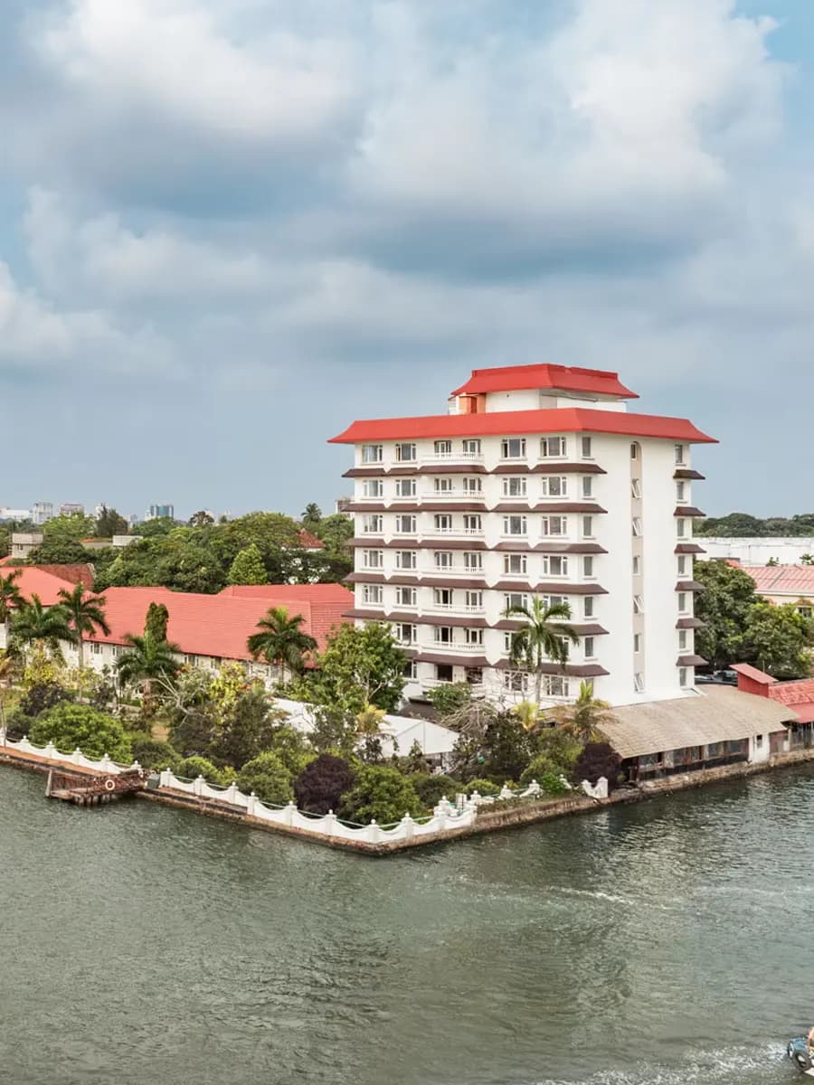 Taj Malabar at sunset, palm fringe and harbour lights across backwater
