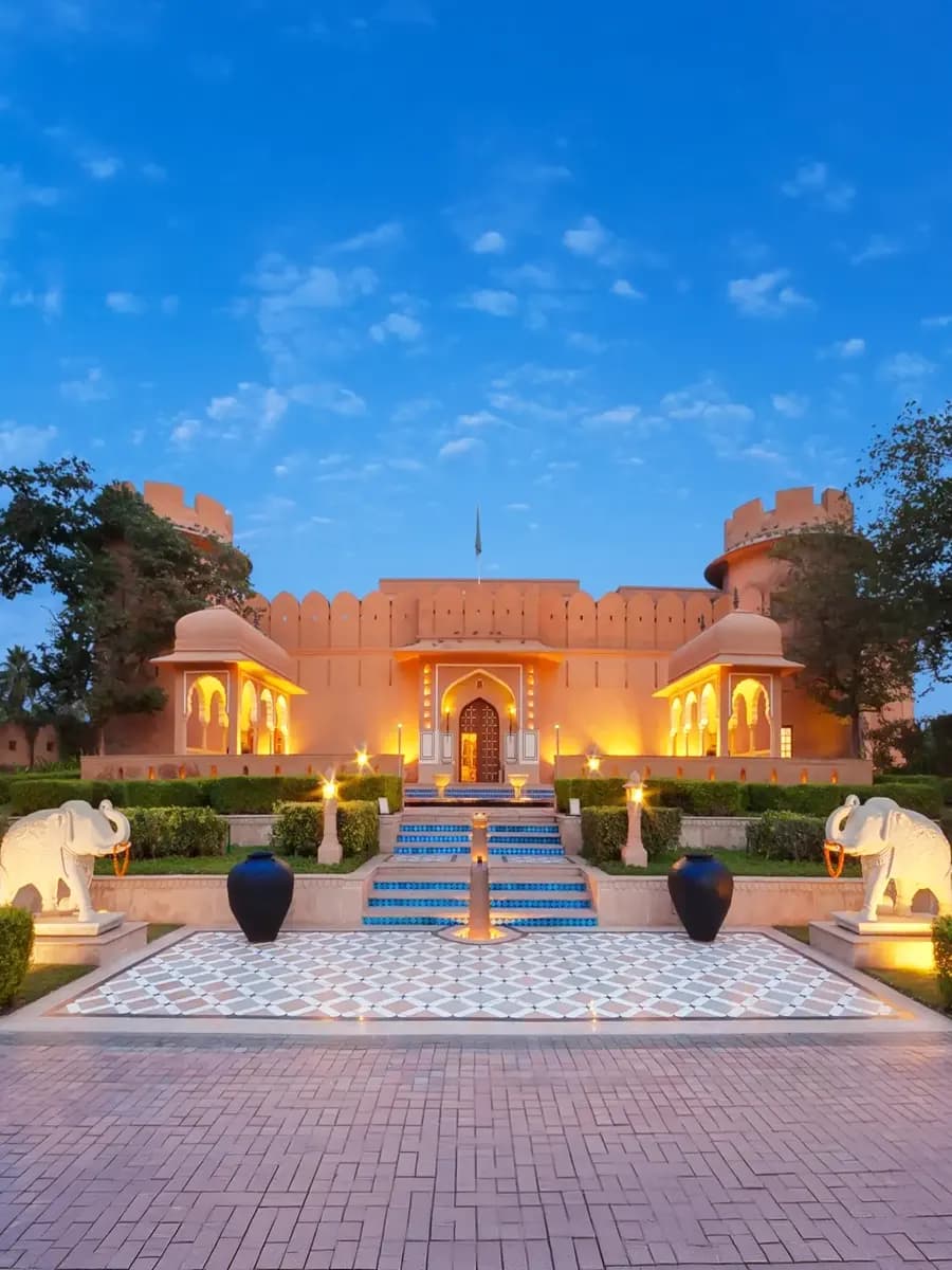 Oberoi Rajvilas haveli courtyard at evening, candle-lit step-well and frangipani