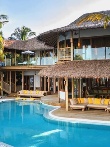 Soneva Fushi beach pavilion at sunset, sand path and lantern light